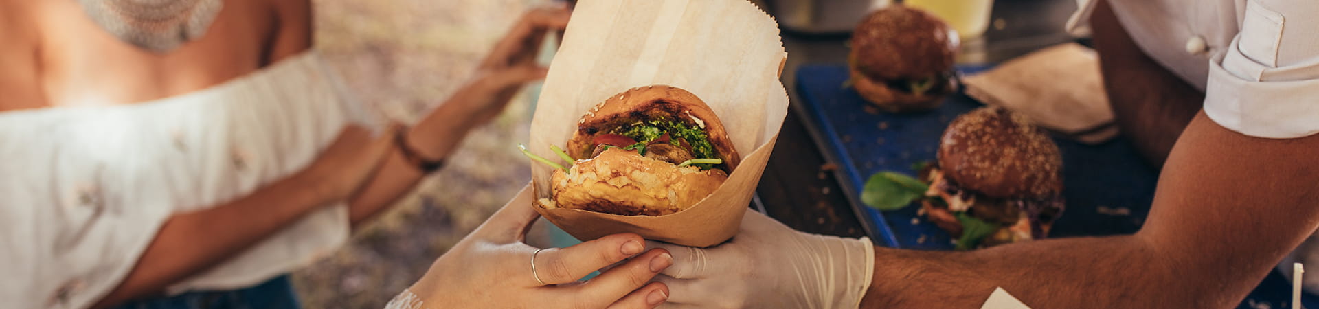 Woman being given a plant-based burger from a man serving at a food truck