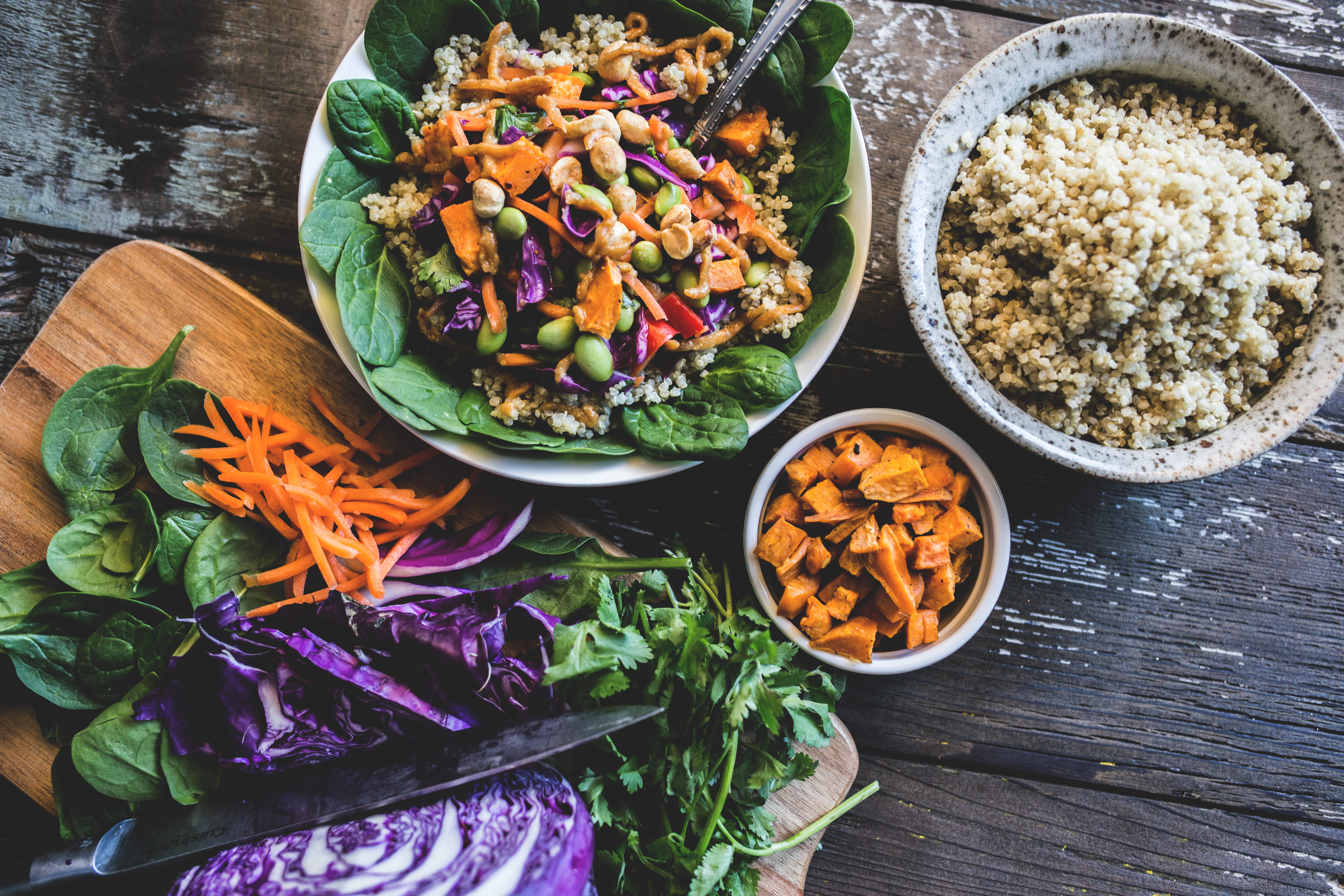 Colourful plant-based bowl with spinach, carrots, cabbage and coconut quinoa on a wooden table